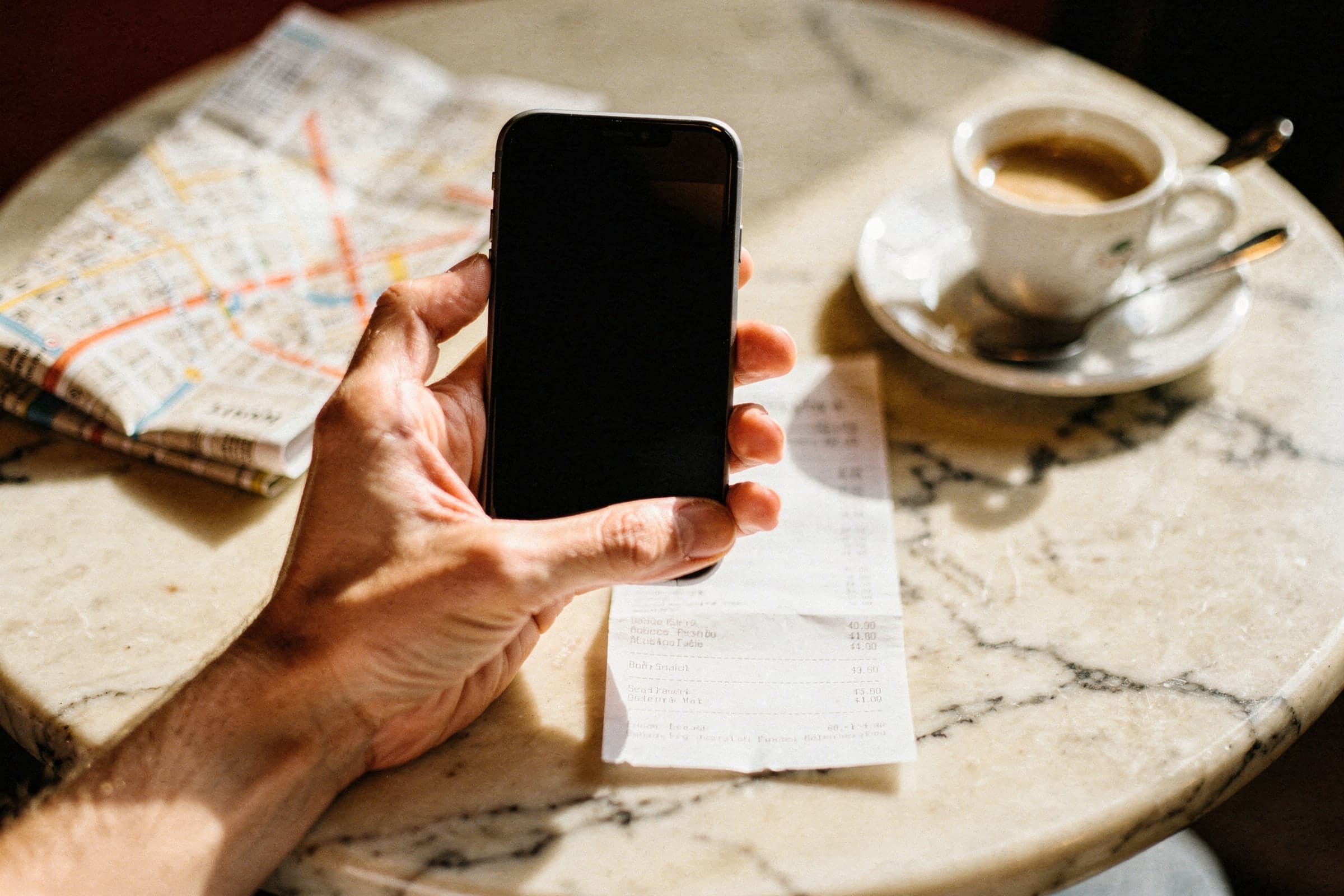 Un artiste photographie un reçu avec son téléphone à la terrasse d'un café